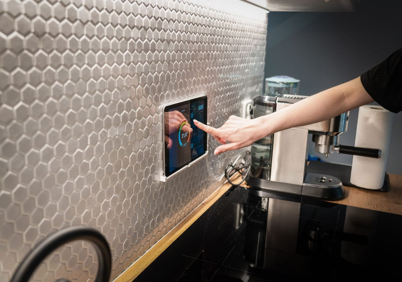 Main réglant une tablette de domotique murale affichant la température
